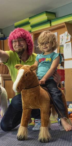 Kinder sitzen auf großen Plüschpferden, werden von Betreuer bespaßt