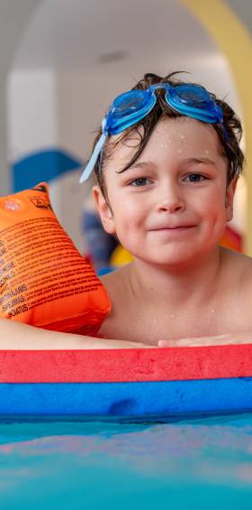 Kind mit Schwimmflügeln im Kinderbecken, sicherer Wasserspaß für die Kleinen