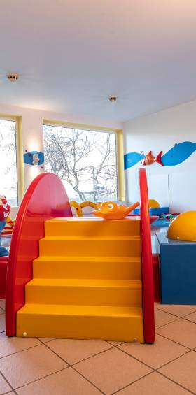 Indoor-Kinderbecken mit gelber Treppe und bunten Elementen, familienfreundlicher Poolbereich