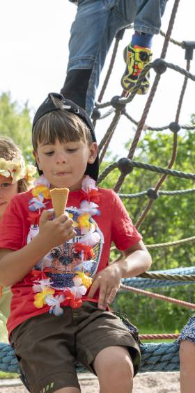 Kinder genießen Eis auf dem Spielplatz, fröhliche Sommermomente im Familotel Mein Krug