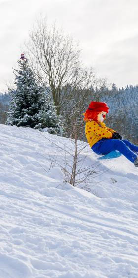 Familotel Maskottchen Happy beim Rodeln mit Kindern