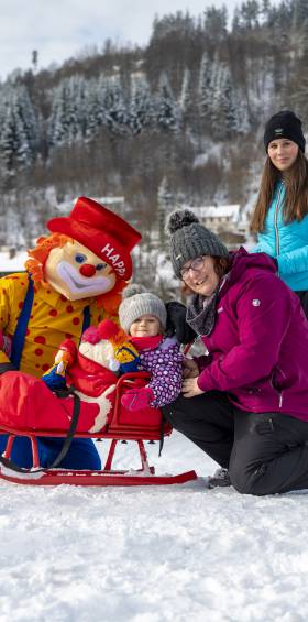 Kinder und Erwachsene genießen das Schlittenfahren auf einer verschneiten Wiese im Winter.