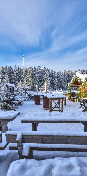 Winterliche Adventsstimmung mit verschneiten Holzbänken und Weihnachtsdekoration 