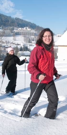 Gruppe von Erwachsenen beim Schneeschuhwandern durch die verschneite Landschaft des Fichtelgebirges