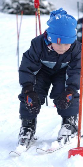 Kind lernt das Skifahren während eines Skikurses für Anfänger 