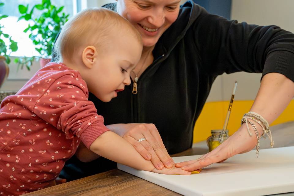 Mutter und Kind gestalten eine Leinwand mit Handabdrücken