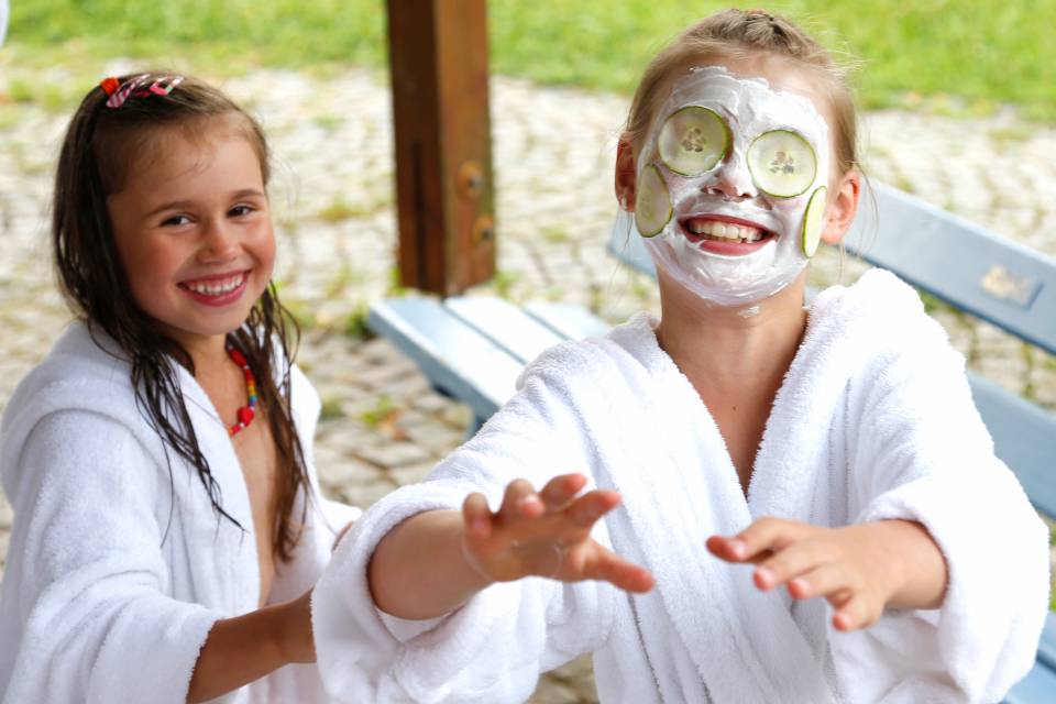 Zwei Kinder mit Gesichtsmasken und Bademänteln, Spaß und Wellness für die Kleinen