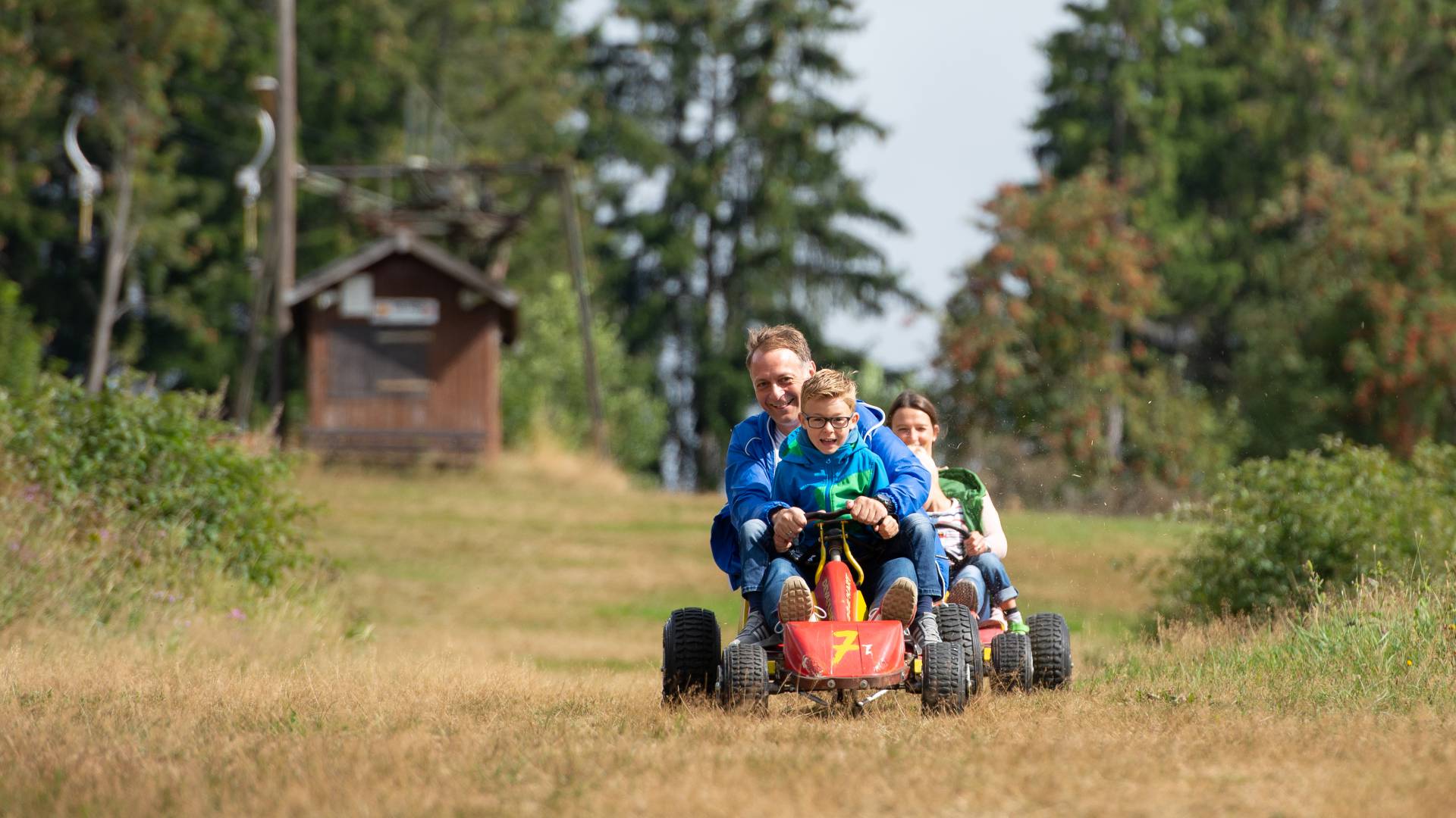 Familie beim Kartfahren auf einer Outdoor-Kartbahn