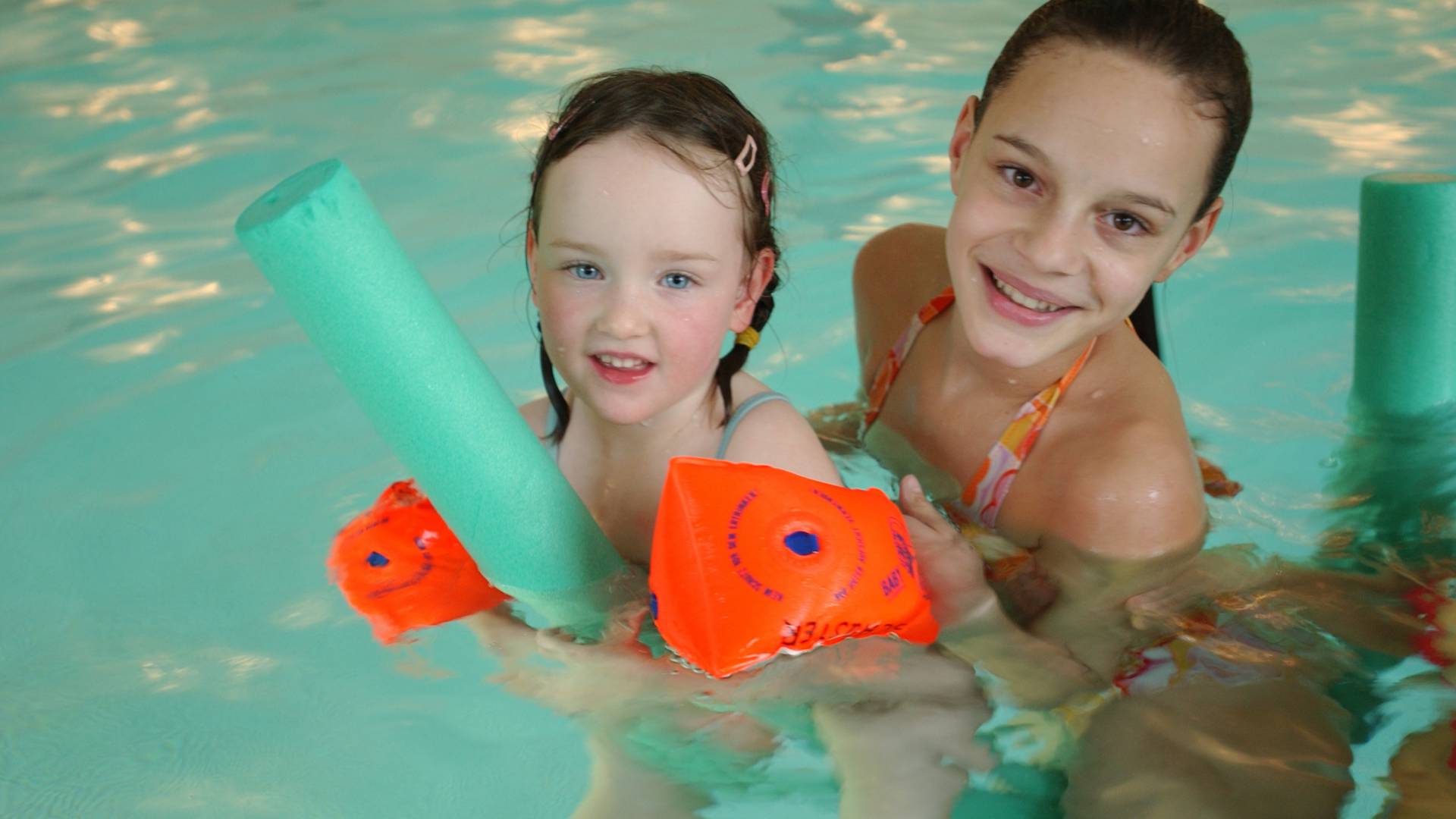 Zwei Kinder mit Schwimmflügeln im Pool