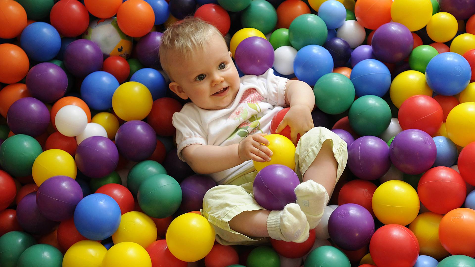 Baby spielt glücklich im bunten Bällebad